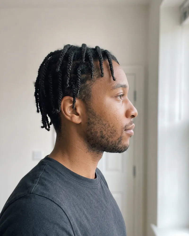 The same man photographed from the side, looking away from the camera.